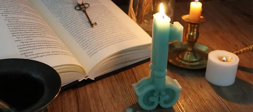 Vela en forma de llave junto a un libro antiguo abierto